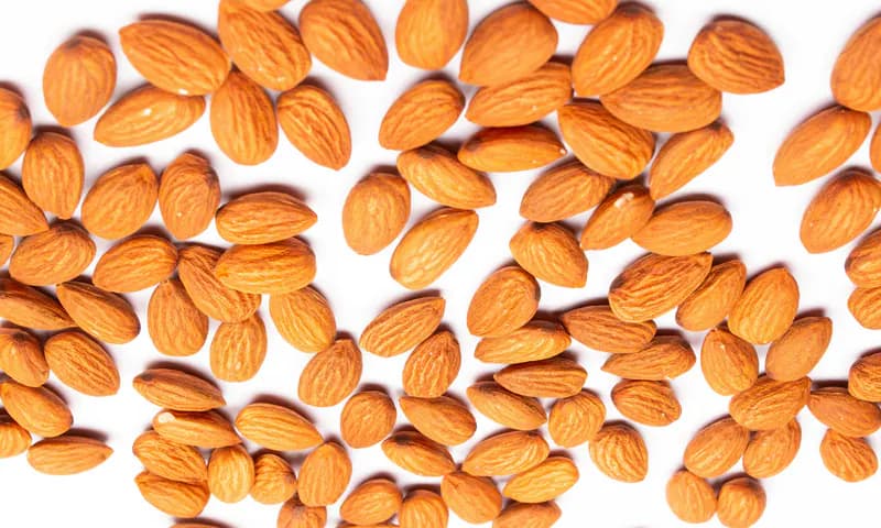 Shelled almond kernels scattered on a white surface